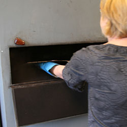 After the powder has whirled up, the plate is placed on a shelf in the cabinet. The asphalt powder slowly falls down on the copper plate.