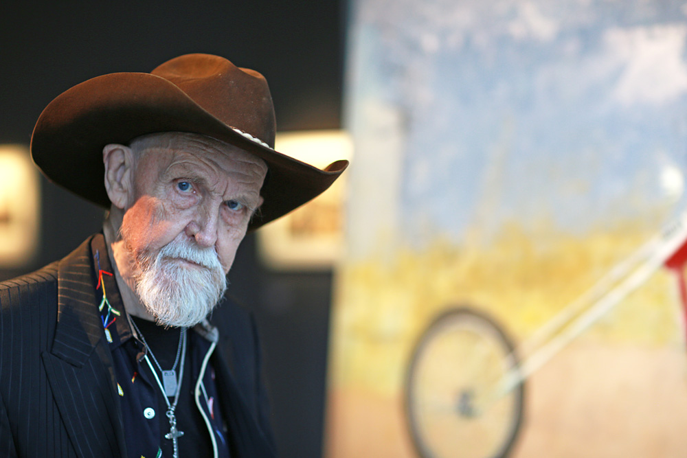 John E Franzén and one of his motorcycle paintings in the background.